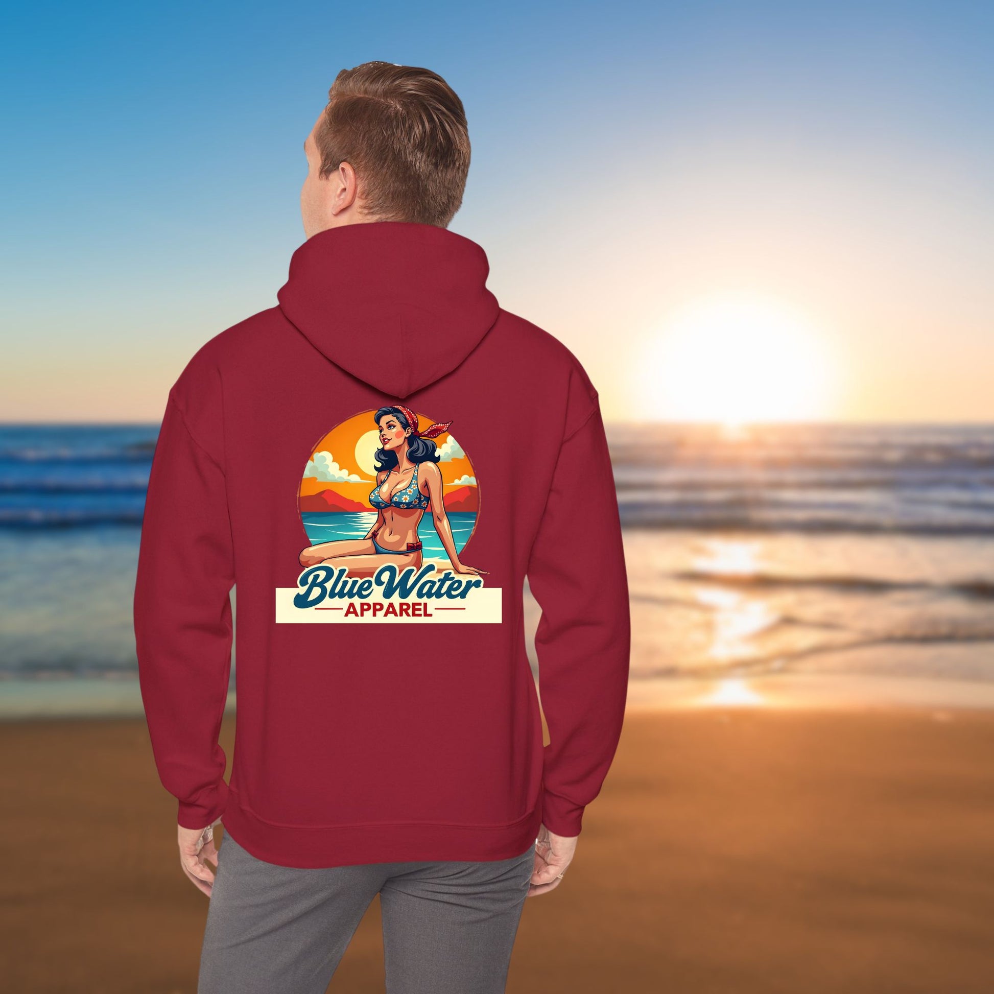 man on beach wearing cardinal red vintage pin-up hoodie by blue water apparel
