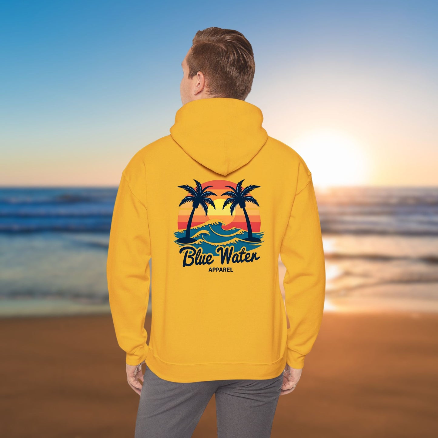 man on beach wearing gold vintage sunset hoodie by blue water apparel