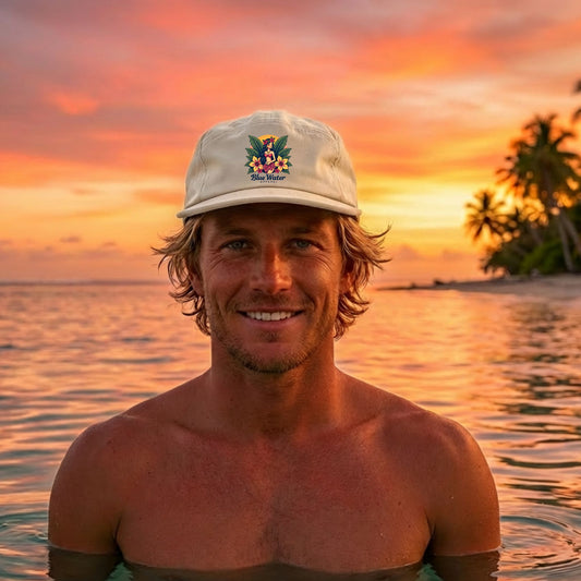 man wearing bone island girl surf cap sitting in tropical waters by blue water apparel