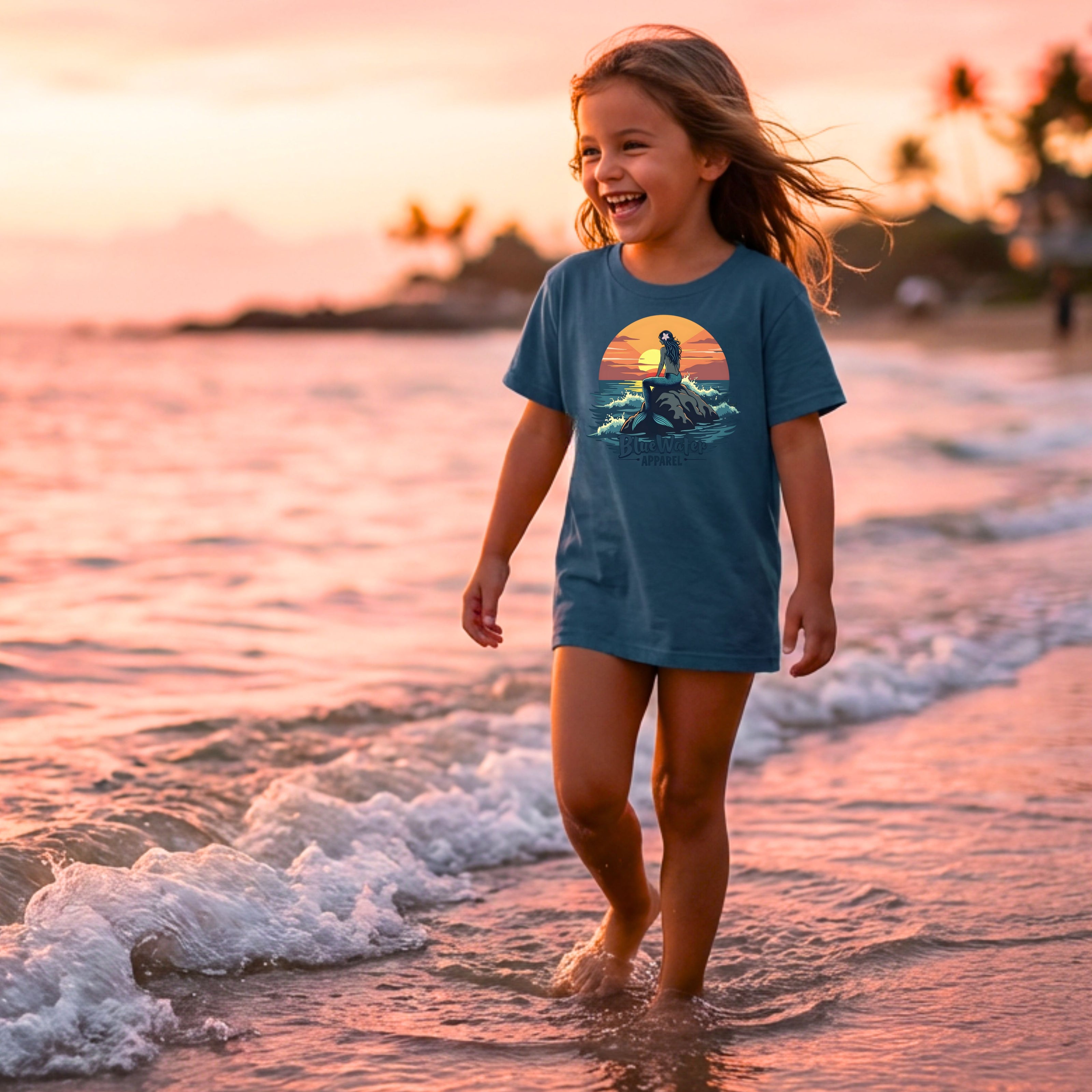 child wearing indigo blue mermaid sunset kids tee walking in water on beach by blue water apparel