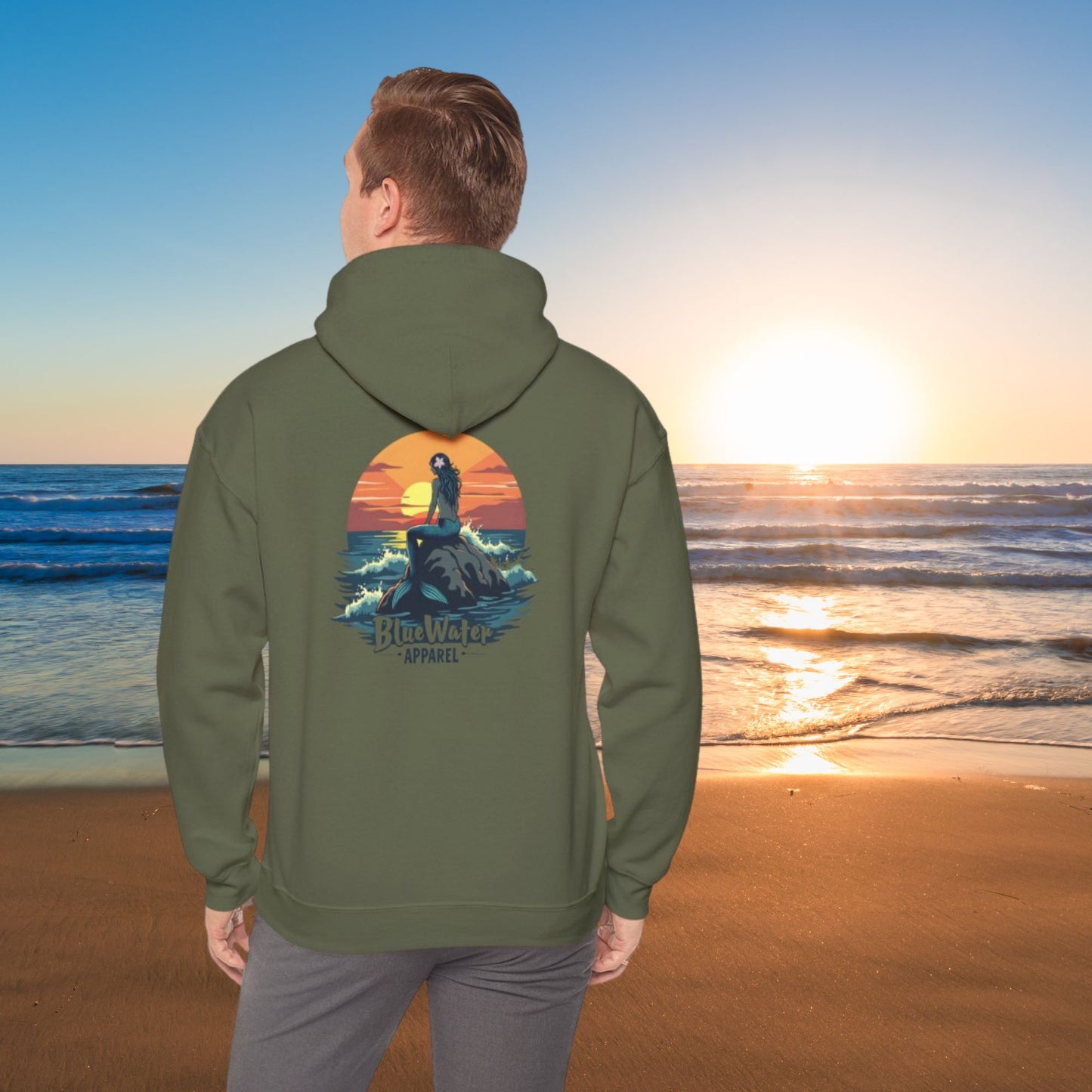 man on beach wearing military green mermaid sunset hoodie by blue water apparel