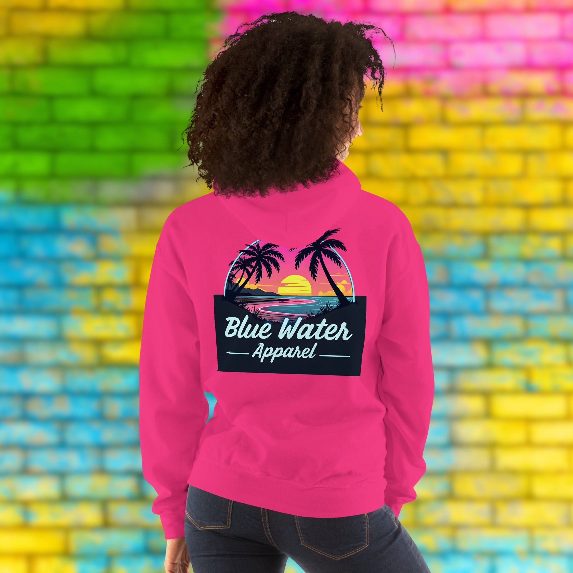 model against neon brick wall wearing heliconia neon sunset hoodie by blue water apparel
