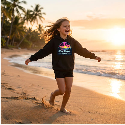 child model wearing black neon sunset kids hoodie running down beach by blue water apparel