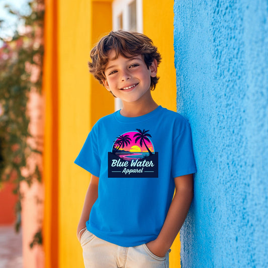  child model wearing sapphire neon sunset kids tee leaning on colorful wall by blue water apparel