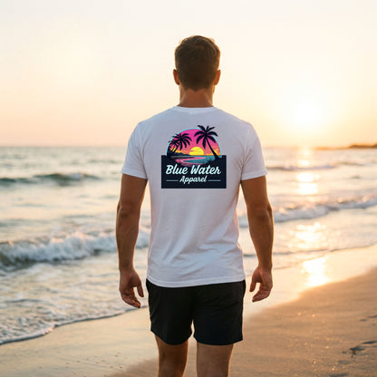 man wearing white neon sunset adult tee walking down beach by blue water apparel