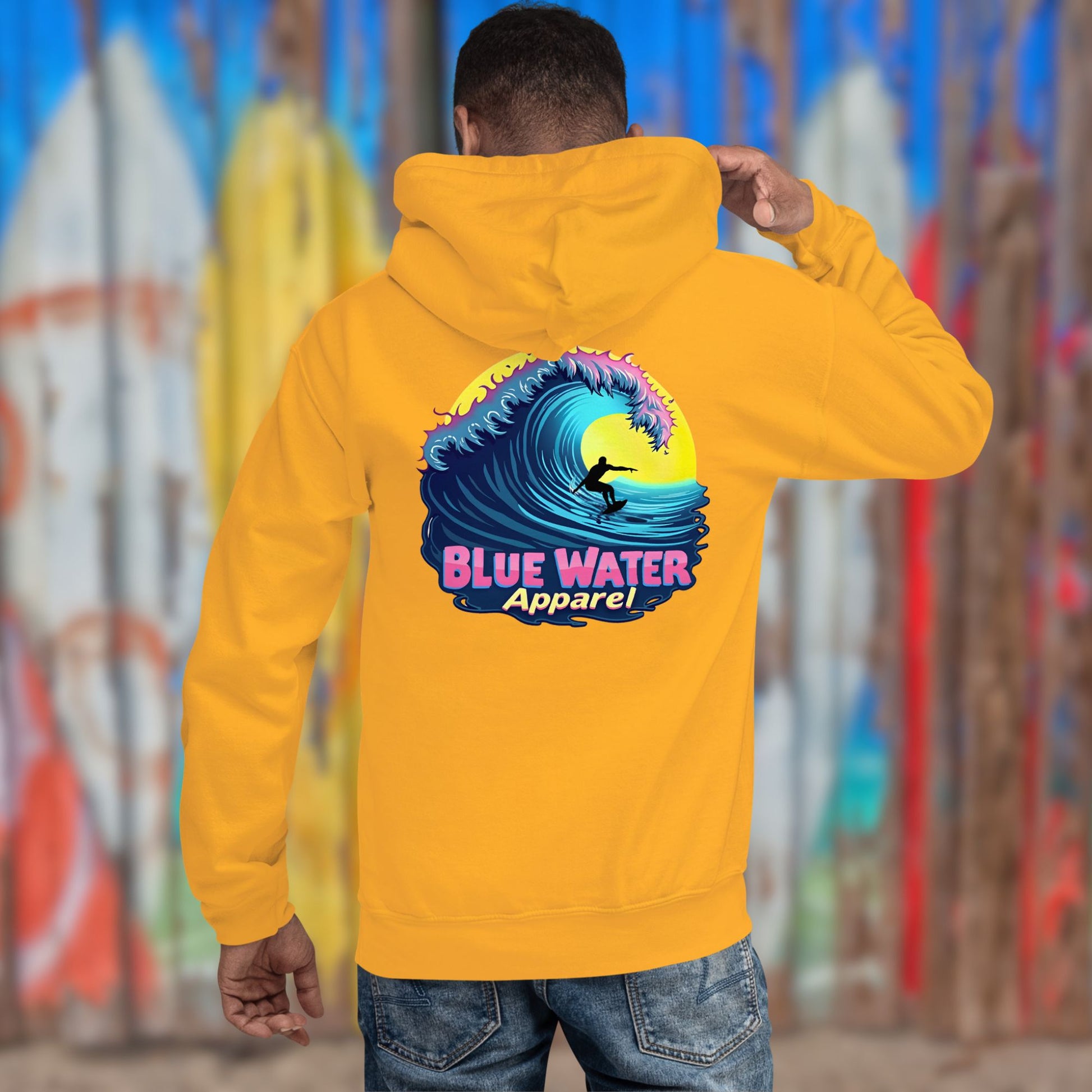 model against surfboard fence wearing gold neon surfer hoodie by blue water apparel