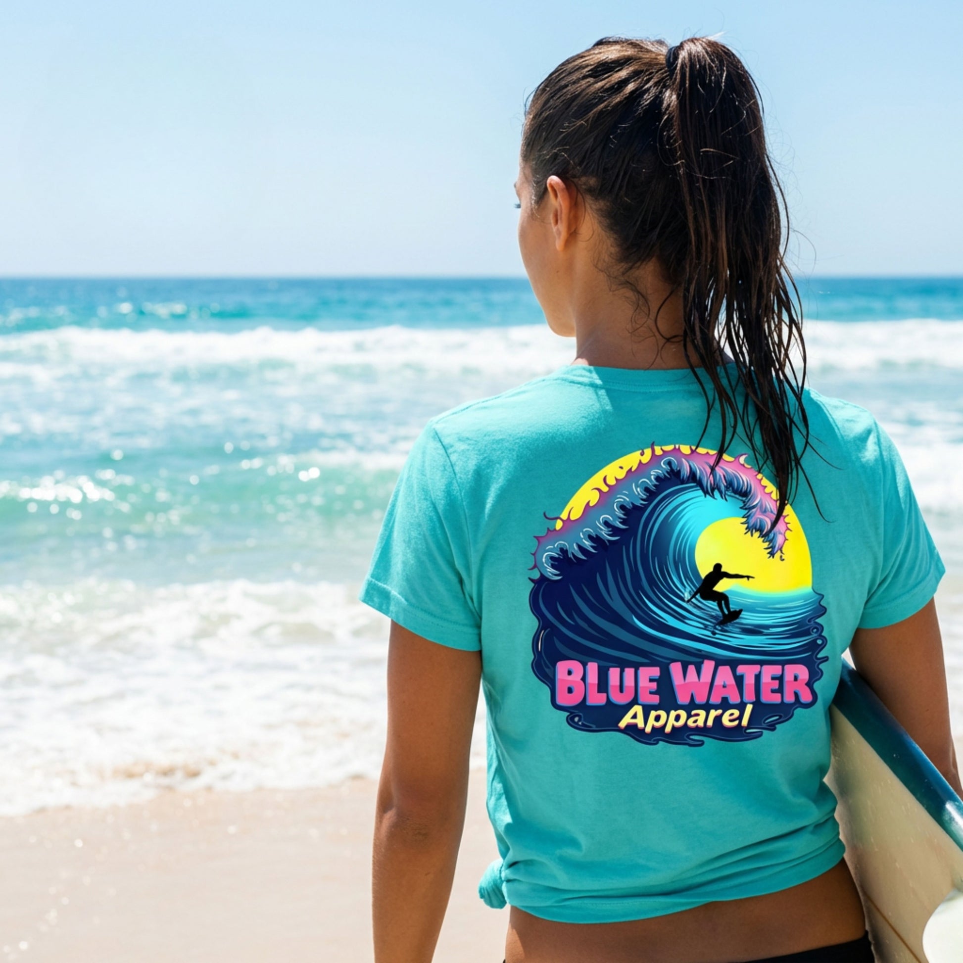 model wearing turquoise neon surfer adult tee on beach with surfboard by blue water apparel