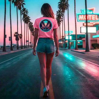 woman wearing charity pink palm tree road adult tee walking down palm tree and neon motel lined road by blue water apparel