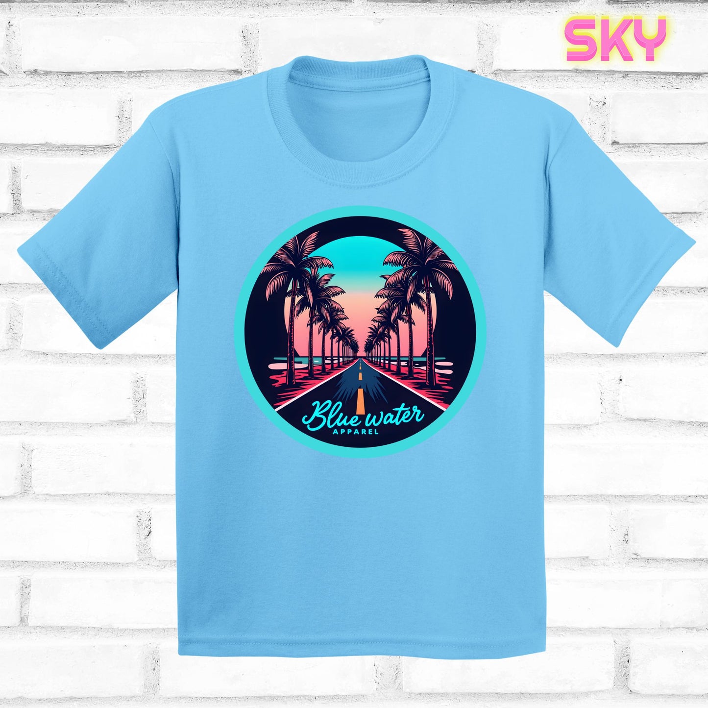 flat lay of sky palm tree road tee by blue water apparel