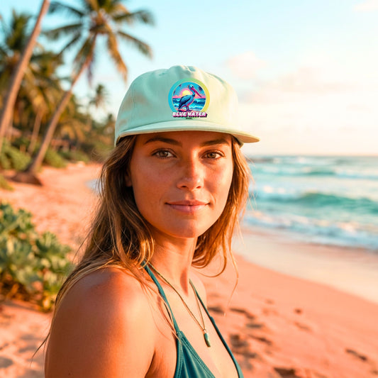 woman wearing mint retro pelican surf cap on tropical beach by blue water apparel