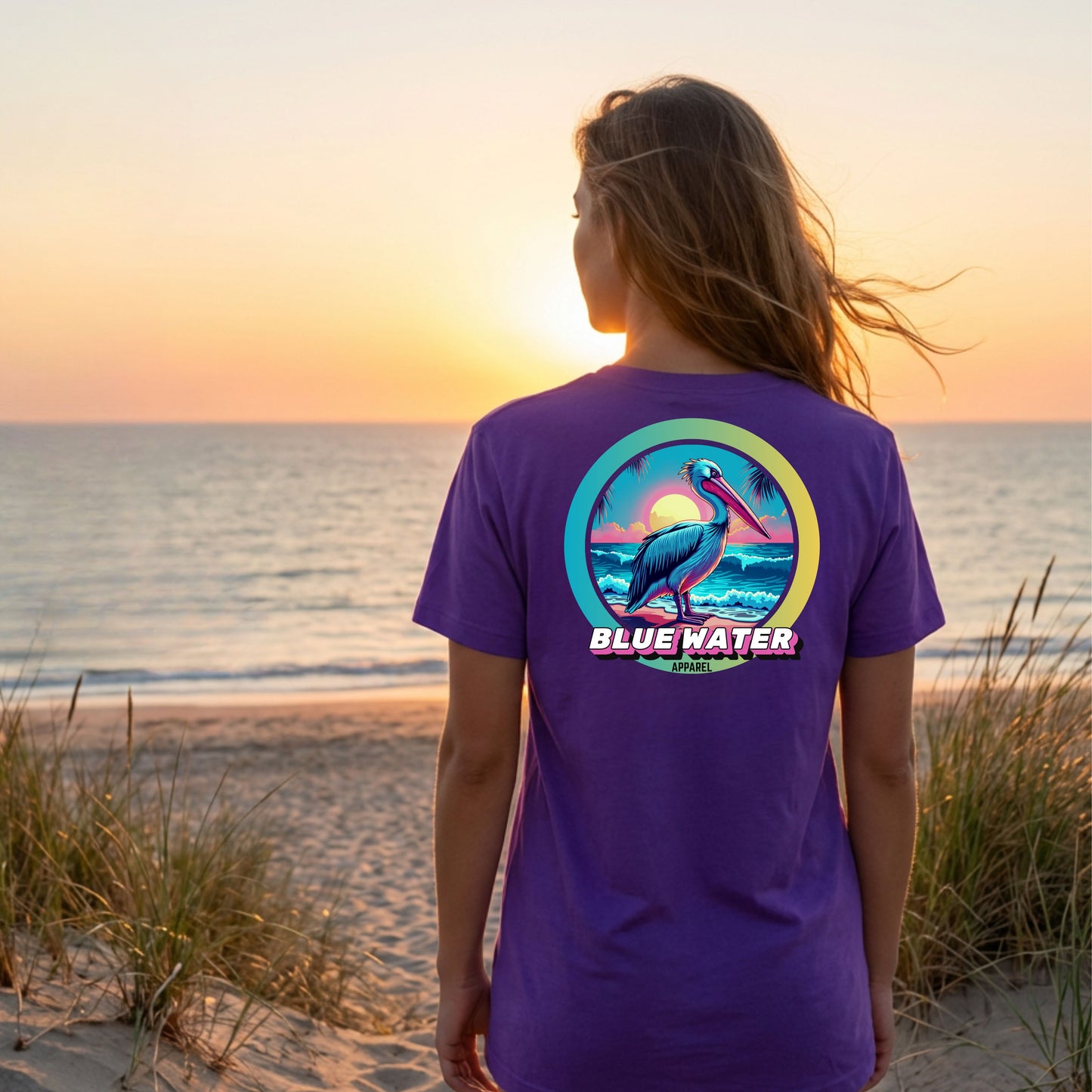 woman wearing team purple retro pelican adult tee standing on beach by blue water apparel