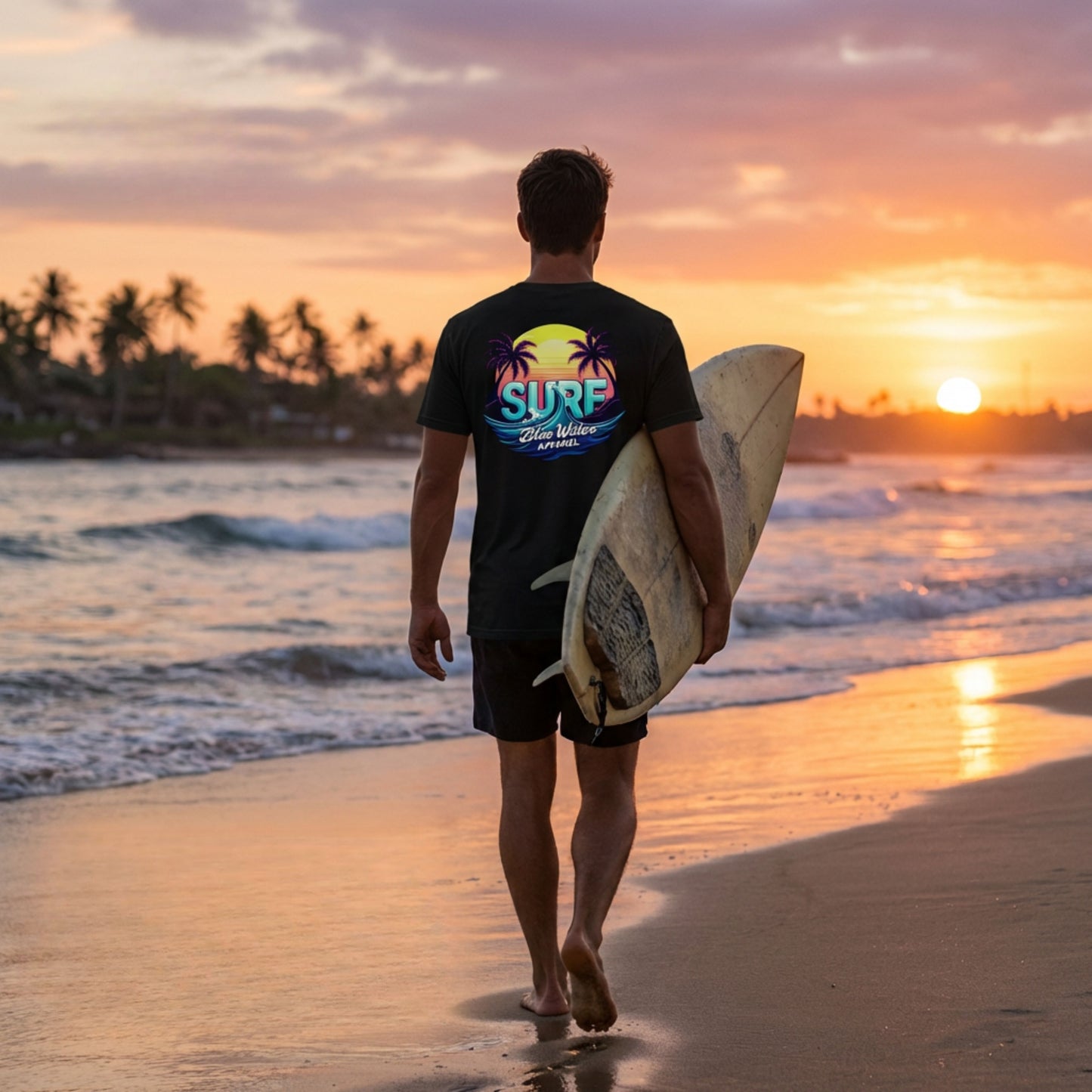 male model wearing retro surf black adult tee walking down beach with surfboard by blue water apparel