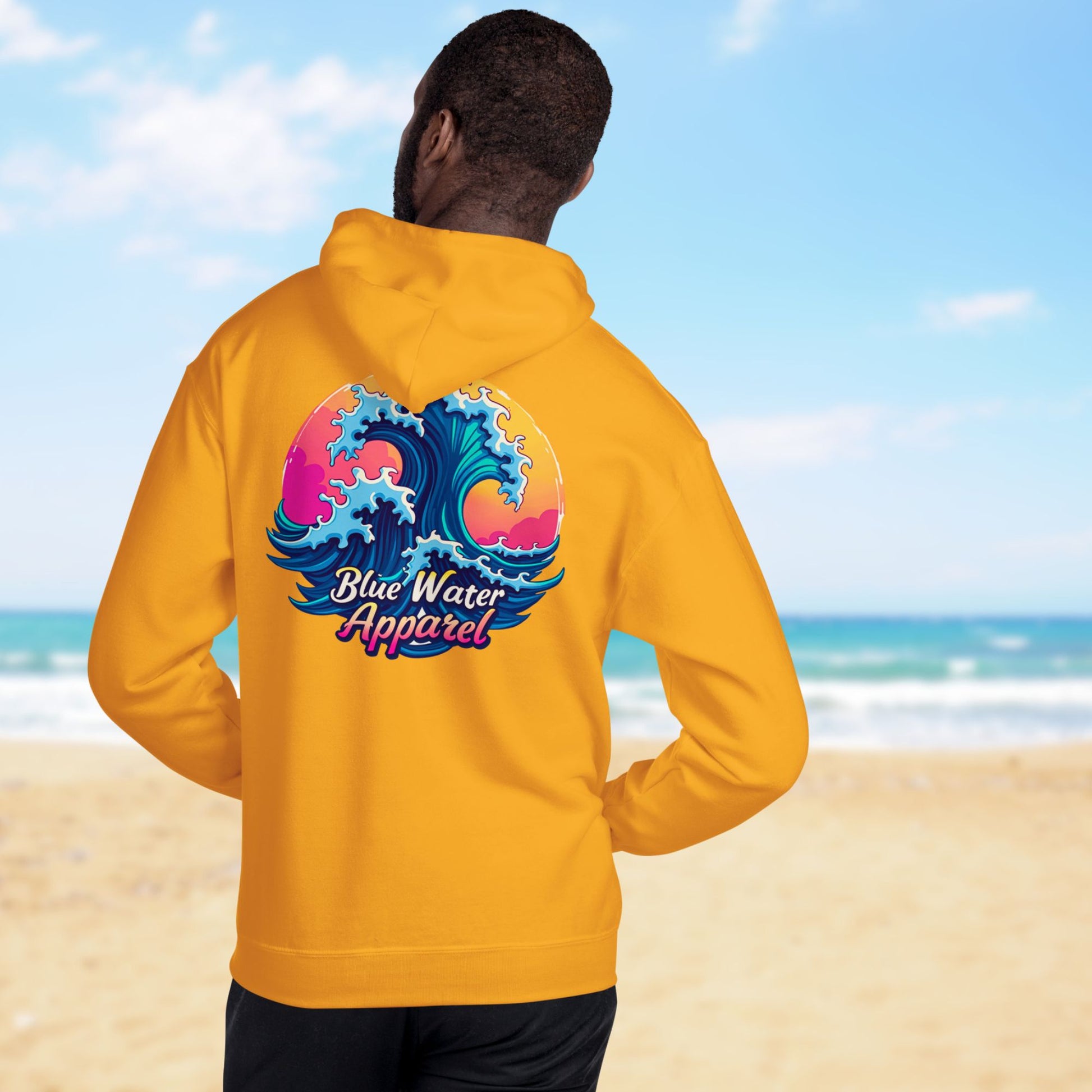man on beach wearing gold retro wave hoodie by blue water apparel