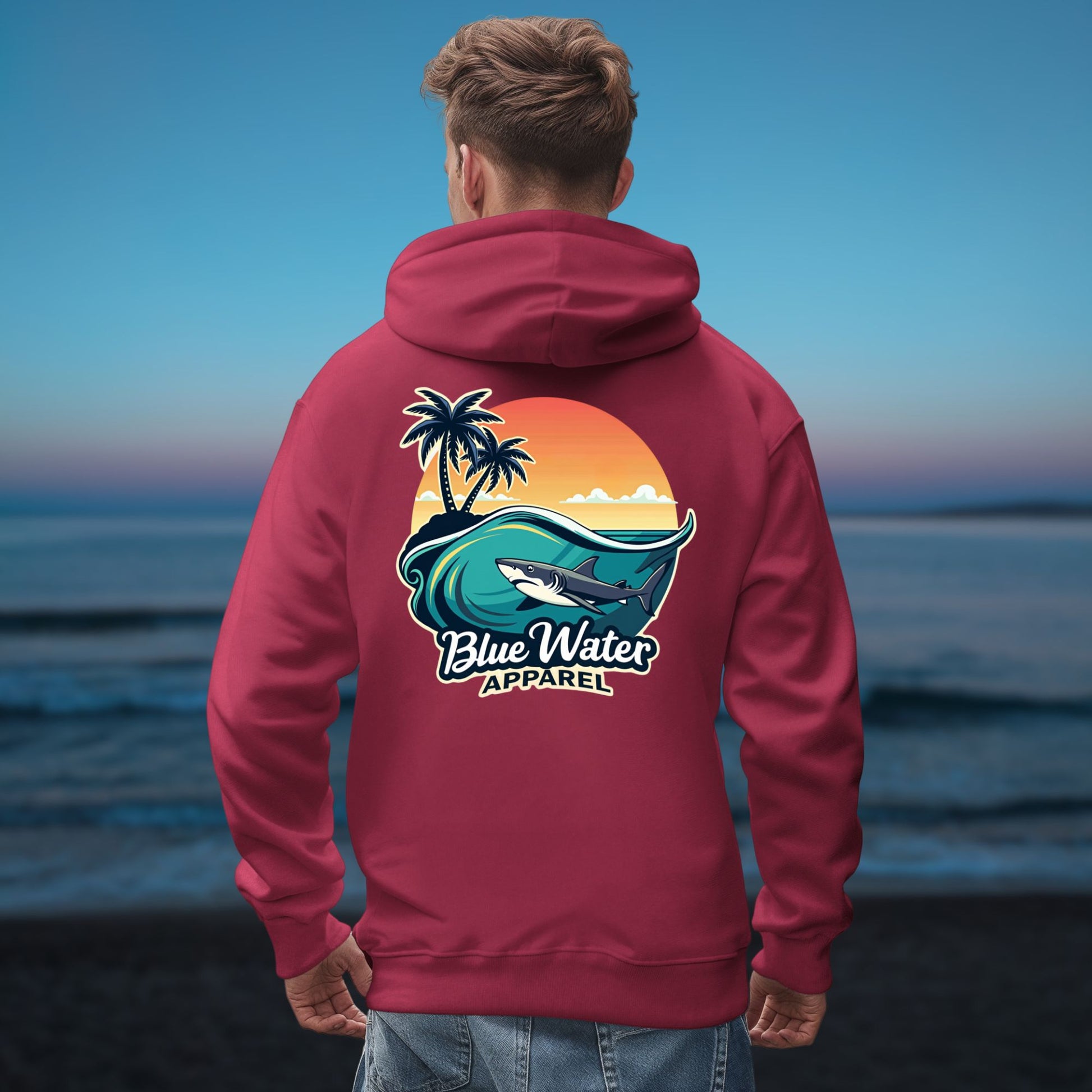 man on beach wearing cardinal red shark wave hoodie by blue water apparel