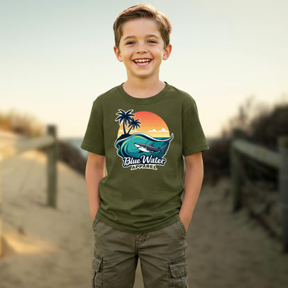 child on beach wearing military green shark wave tee by blue water apparel