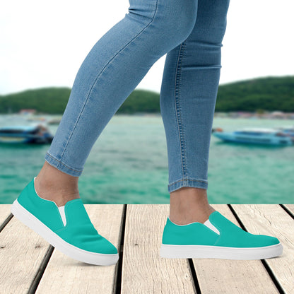 Teal slip-on shoes worn with blue jeans by a waterfront