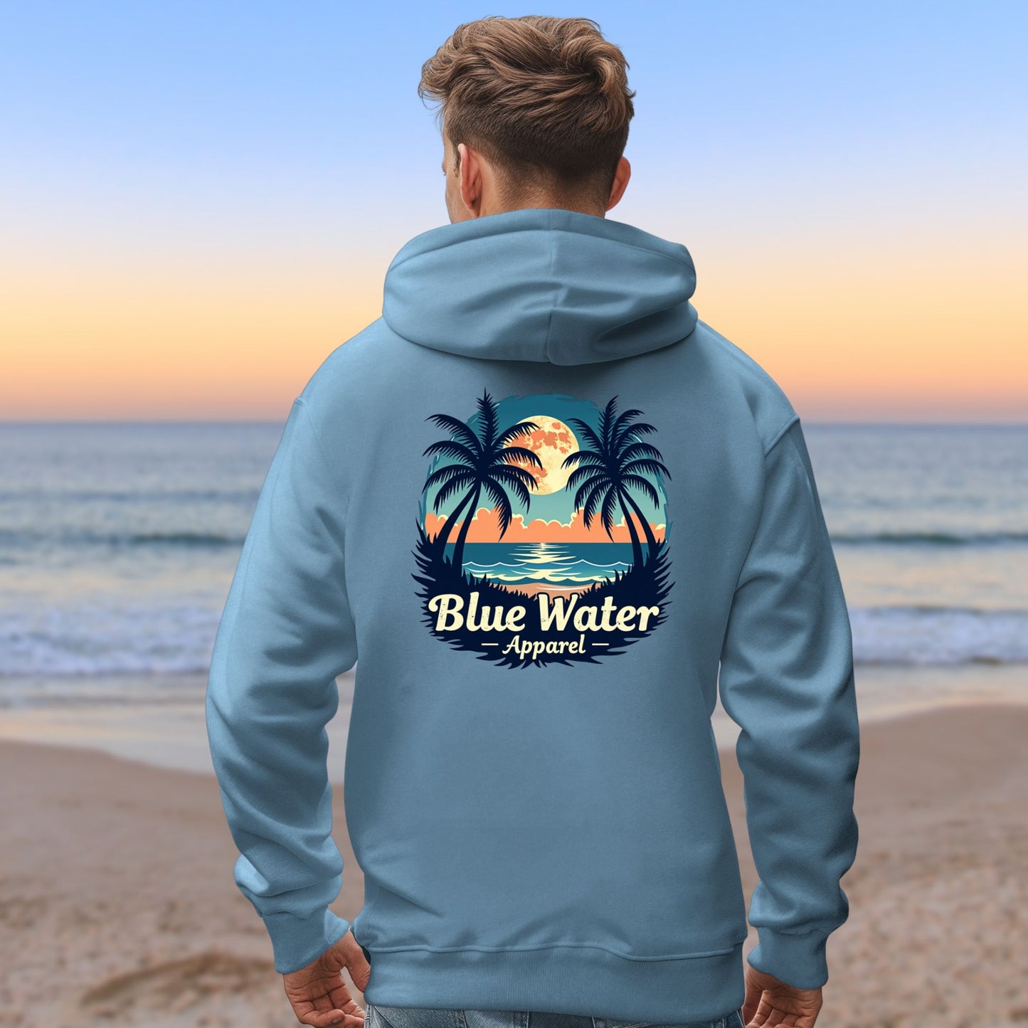 male model on beach wearing indigo blue tropical moon hoodie by blue water apparel