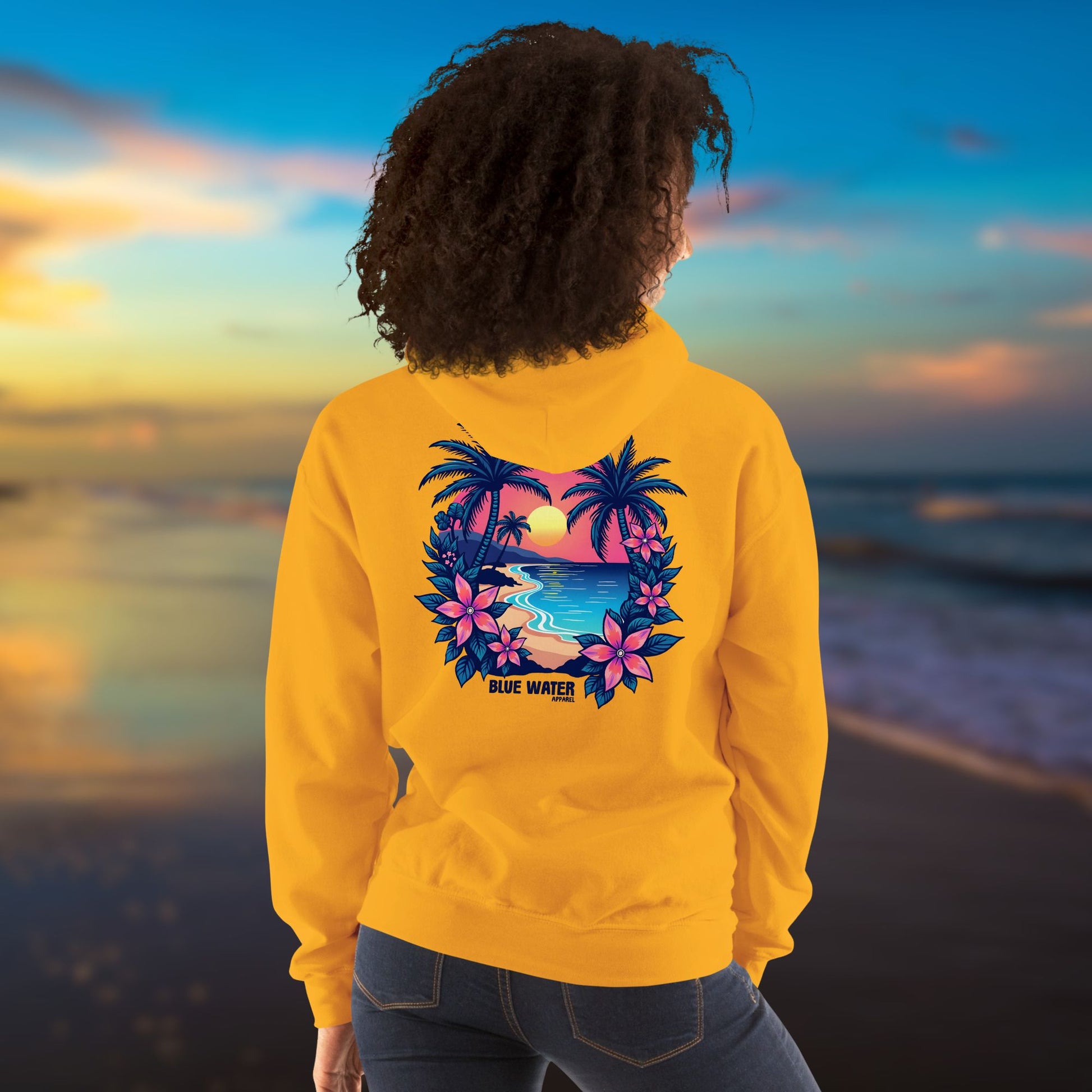 model on beach wearing gold tropical sunset hoodie by blue water apparel