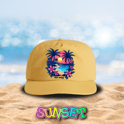 flat lay sunset tropical sunset surf cap on beach by blue water apparel