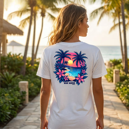 model wearing white tropical sunset adult tee on beach resort sidewalk by blue water apparel