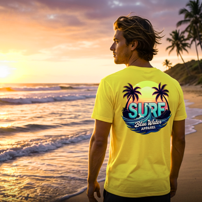 male model wearing yellow retro surf tee on beach by blue water apparel