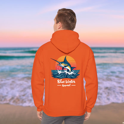 man on beach wearing orange vintage marlin hoodie by blue water apparel