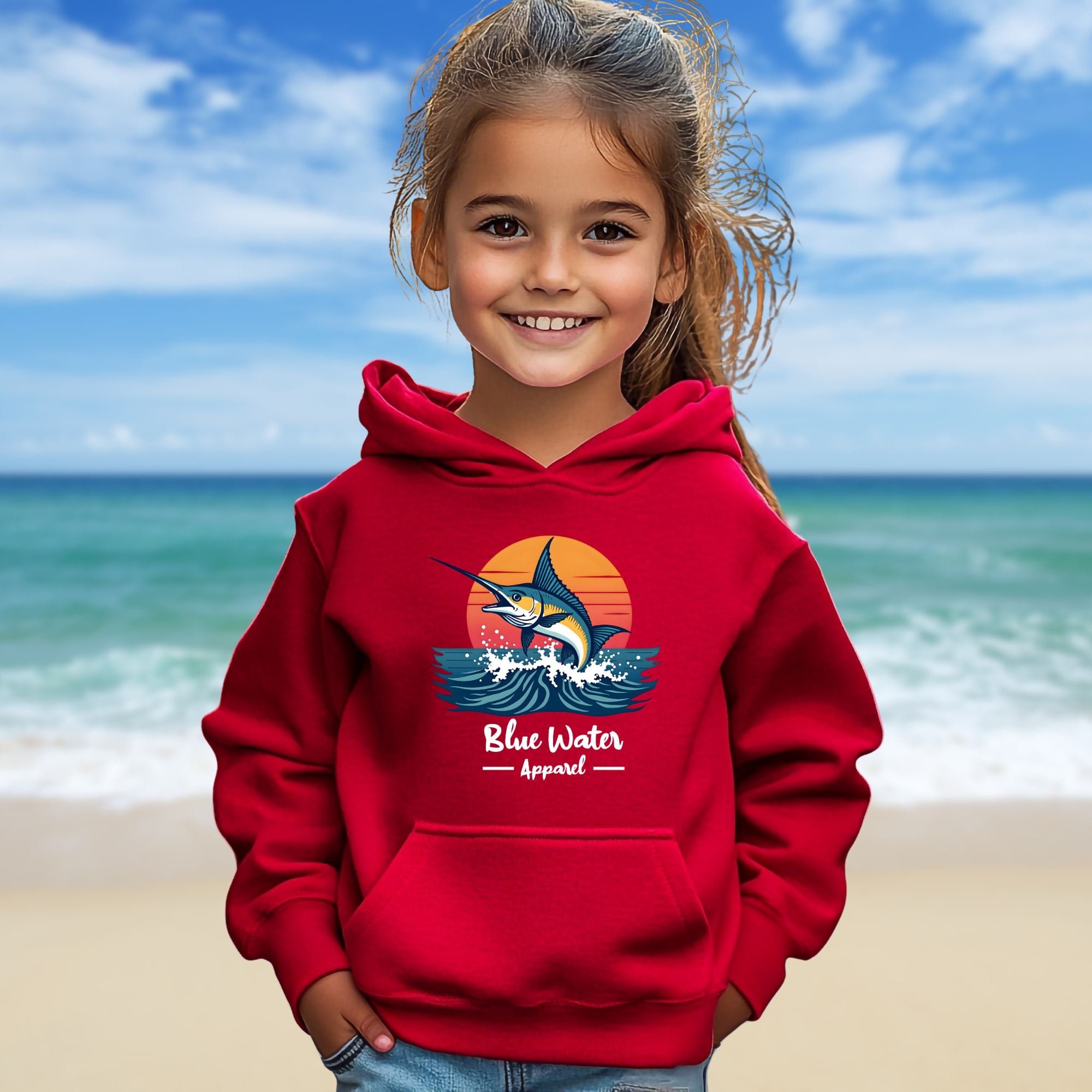 child model on beach wearing red vintage marlin kids hoodie by blue water apparel