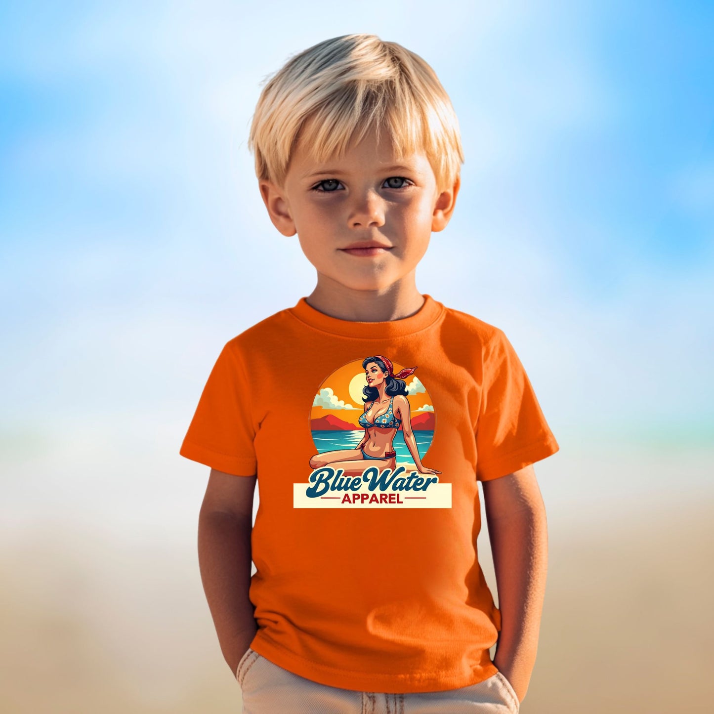 male child on beach wearing orange vintage pin up tee by blue water apparel