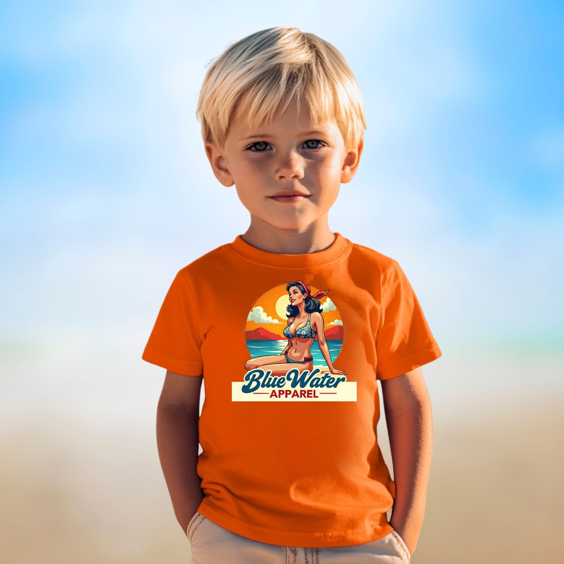 male child on beach wearing orange vintage pin up tee by blue water apparel