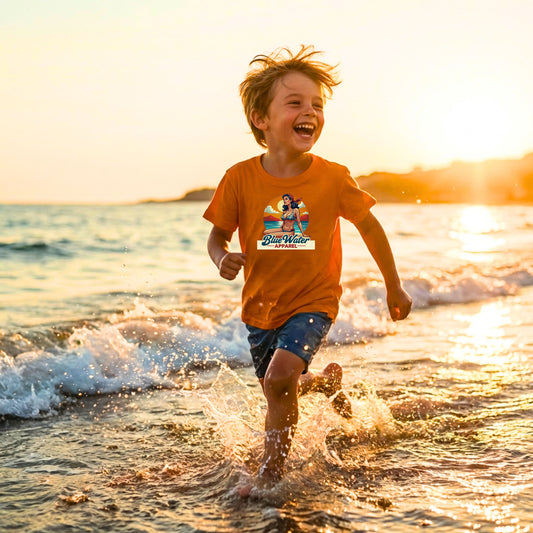 child wearing orange vintage pin-up kids tee running down beach by blue water apparel