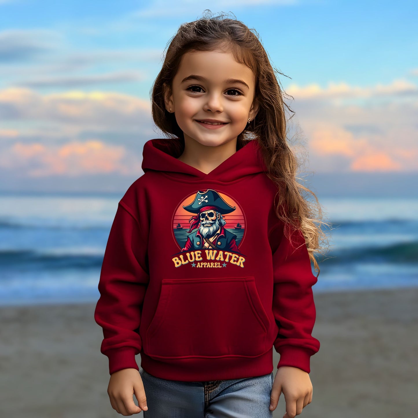child model on beach wearing cardinal red vintage pirate kids hoodie by blue water apparel