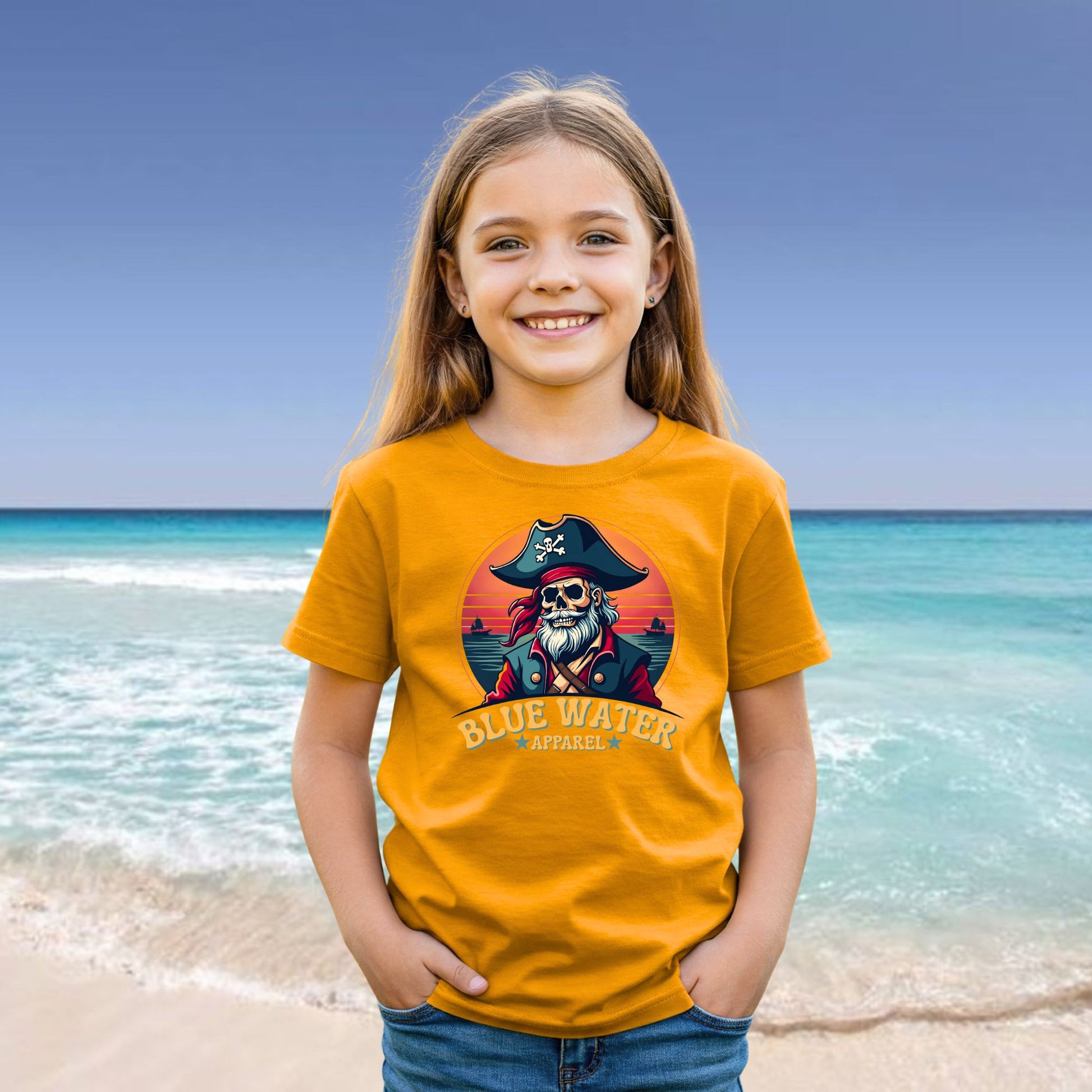 female child on beach wearing gold vintage pirate tee by blue water apparel