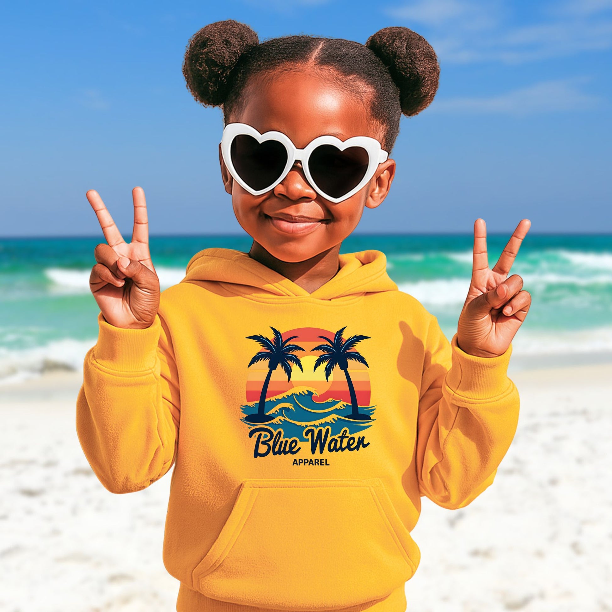 child model on beach wearing gold vintage sunset kids hoodie by blue water apparel
