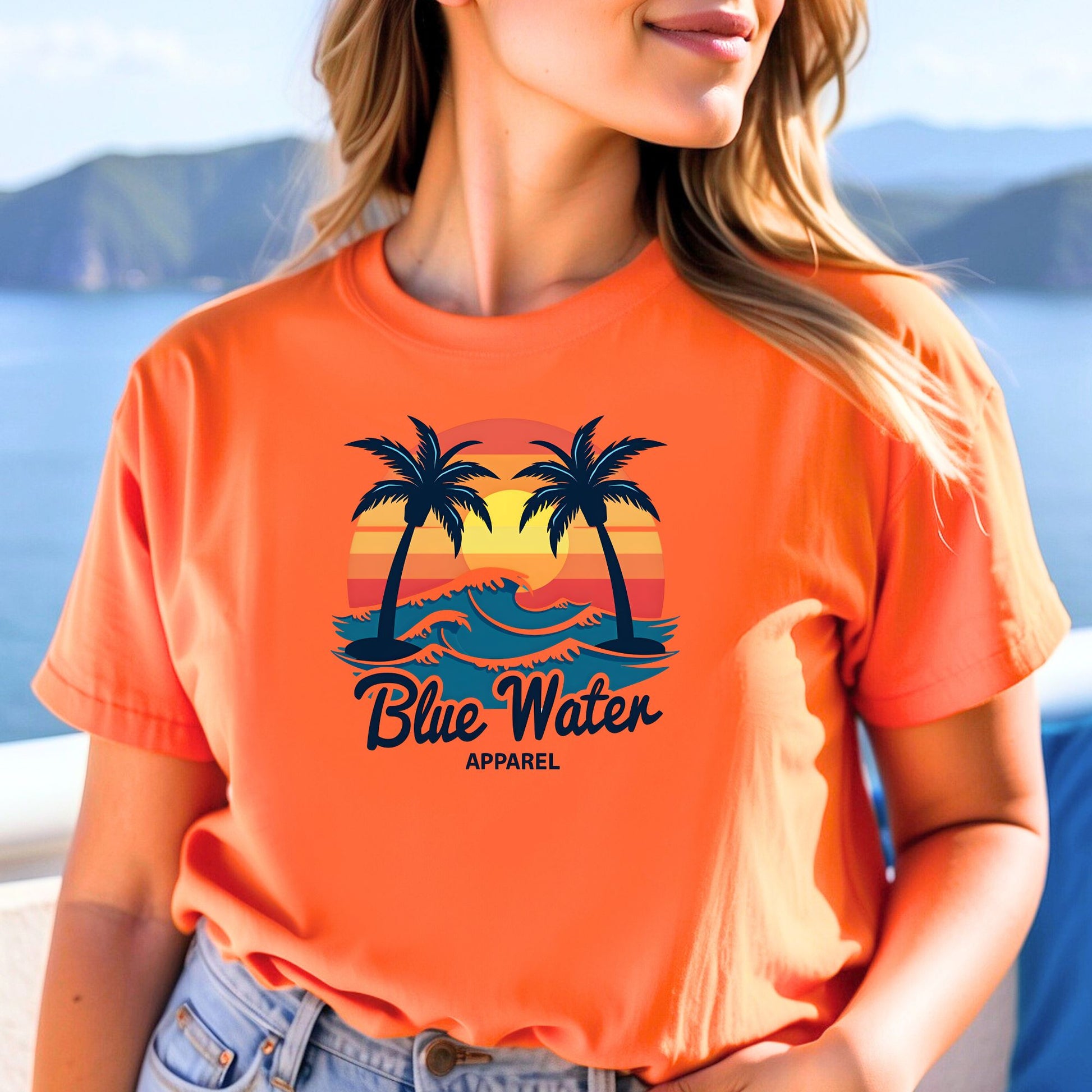 model wearing an orange vintage sunset tee by blue water apparel with beach background