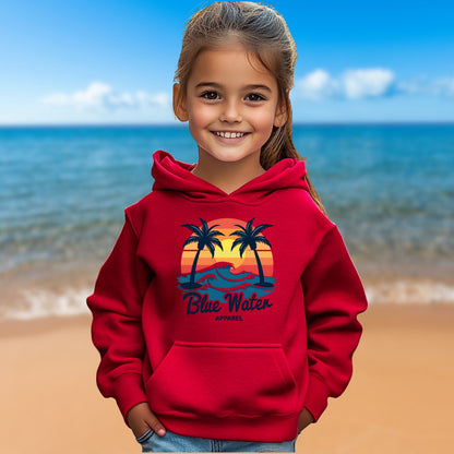 child model on beach wearing red vintage sunset kids hoodie by blue water apparel