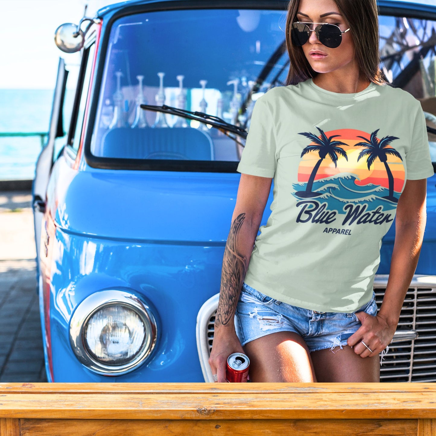 Model leaning on old vw van wearing a sage vintage sunset tee by blue water apparel