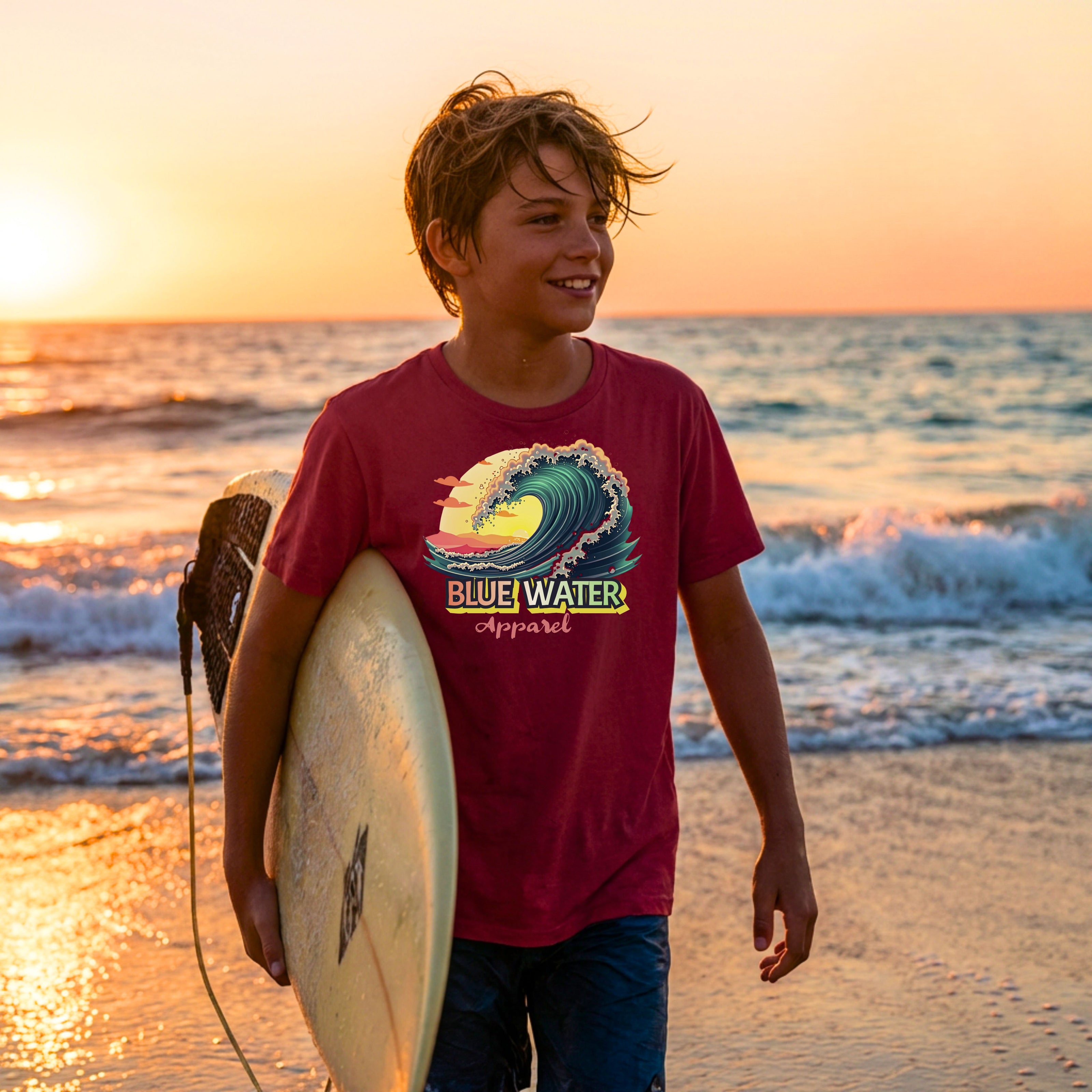 kid wearing cardinal red vintage surf kids tee coming out of water with surfboard by blue water apparel