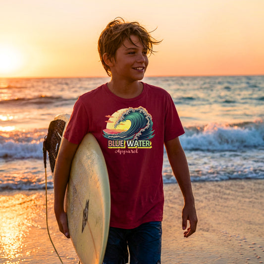 kid wearing cardinal red vintage surf kids tee coming out of water with surfboard by blue water apparel