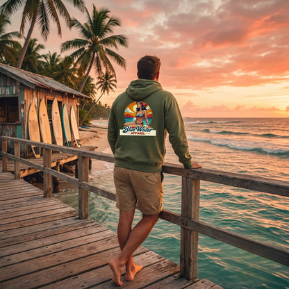 man wearing military green vintage pin-up hoodie on deck of surf shack by blue water apparel