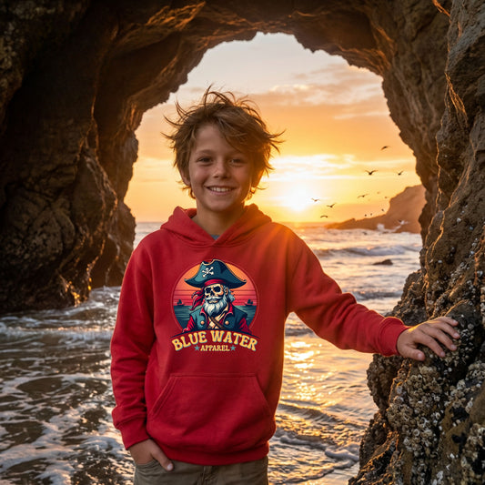 boy wearing cardinal red vintage pirate kids hoodie inside beach cave by blue water apparel
