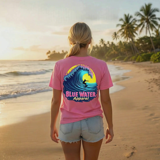 music video of model wearing charity pink neon surfer adult tee standing on beach by blue water apparel