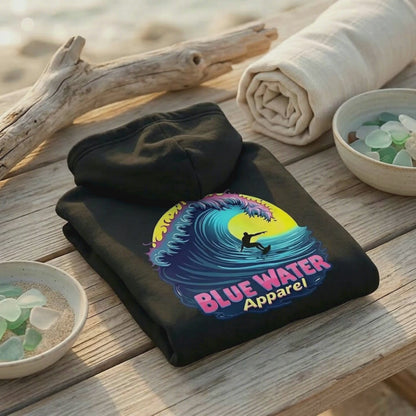 video of black neon surfer hoodie folded up on beach table with beach sounds by blue water apparel